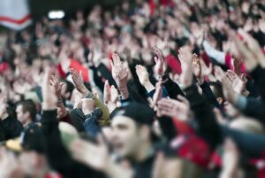 Hundred of people in a stadium raising their hands