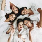 Young bachelorettes dressed in white laying on a bed
