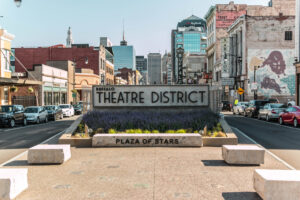 A photo of the Theatre District plaza sign on a sunny day in downtown Buffalo