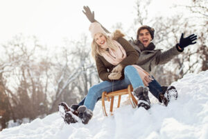 A young couple slides down a snowy hill on a sled in Buffalo during the winter