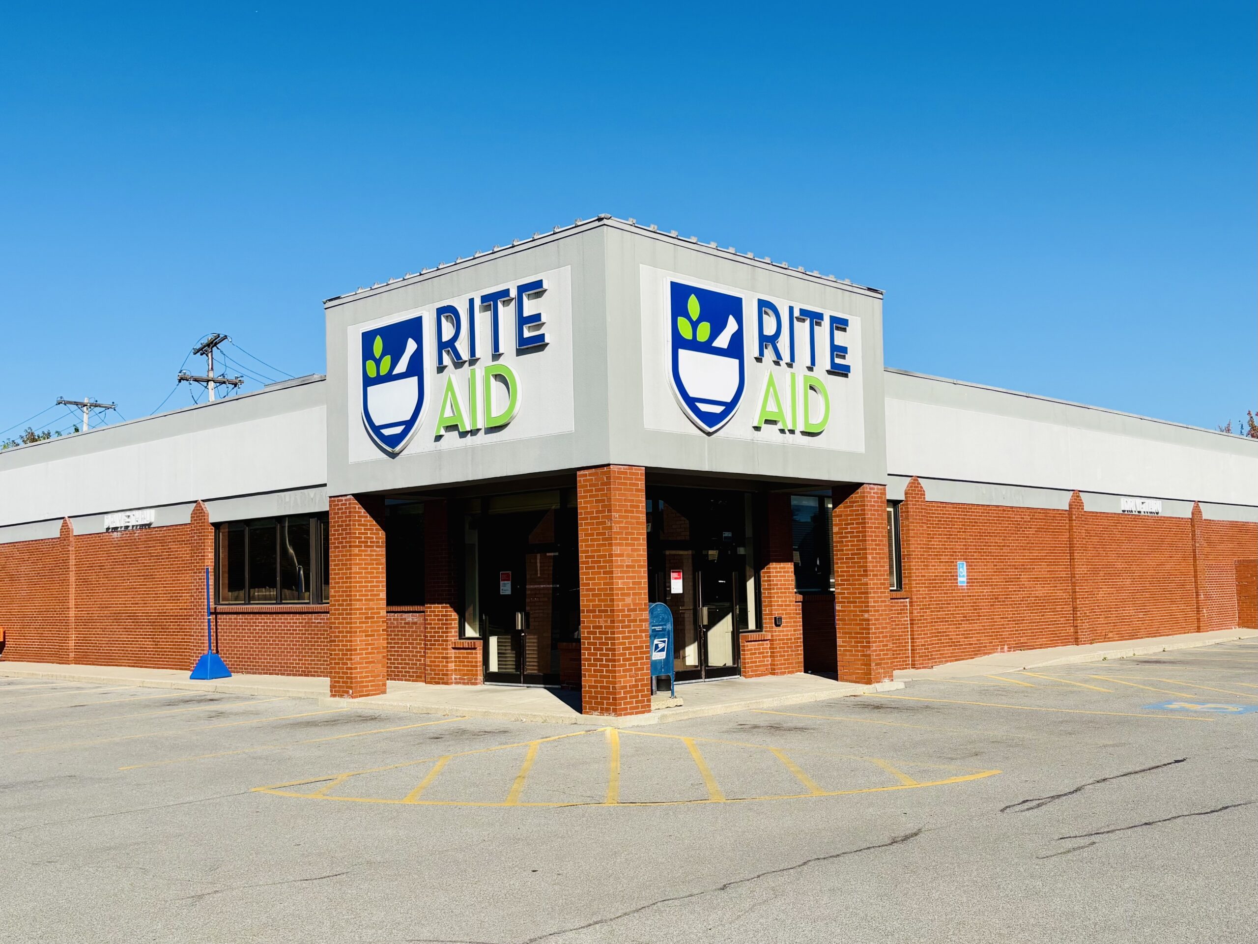 Brick commercial building with Rite Aid signage, front parking, and corner visibility.